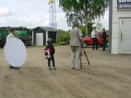 Filmteam med kamera och reflexskärm på en grusplan